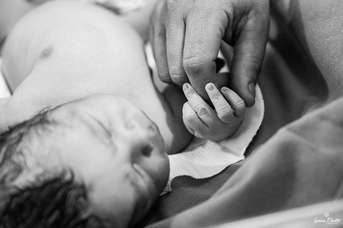 Foto de bebe recém nascido segurando a mão do pai 