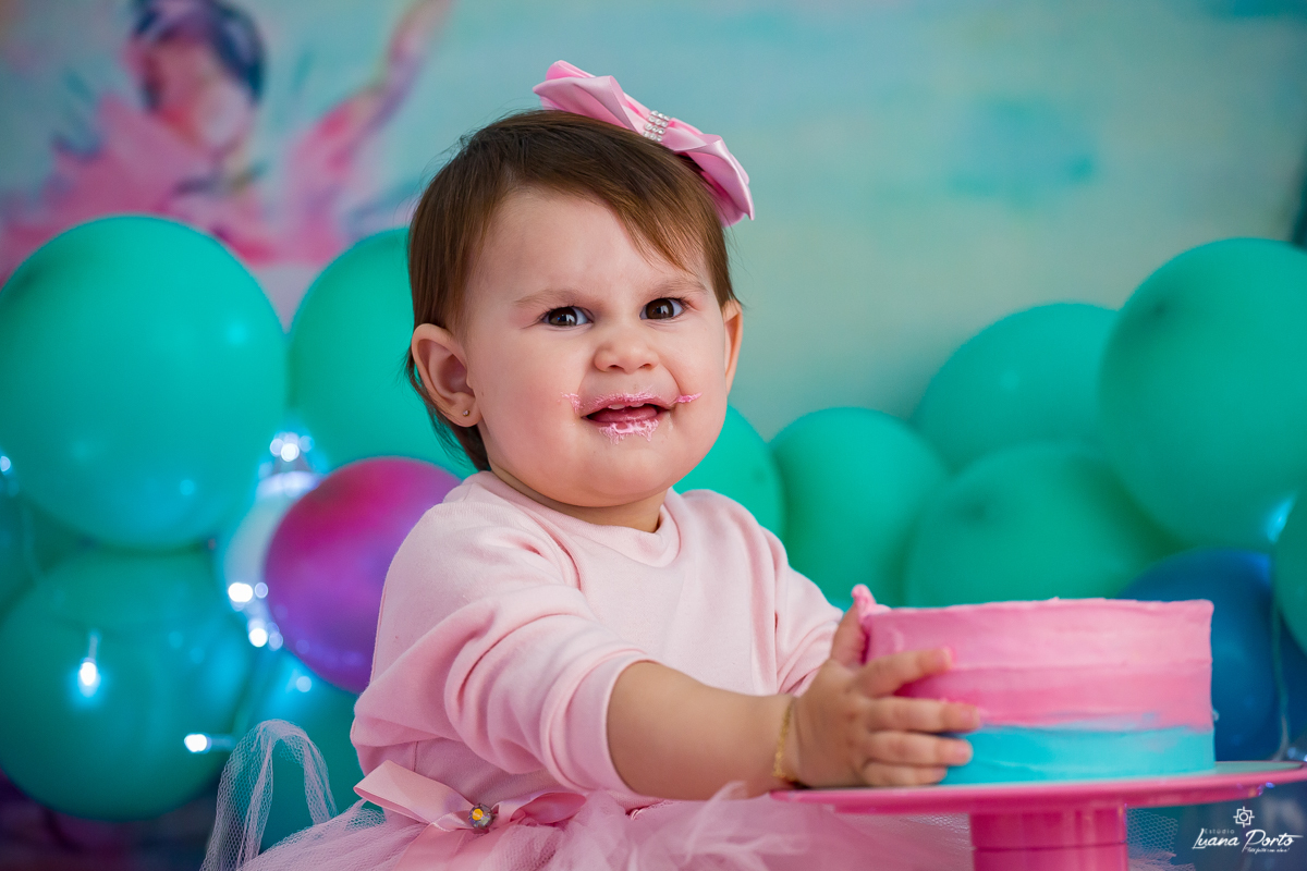 Menina com mão no bolo do smash the cake