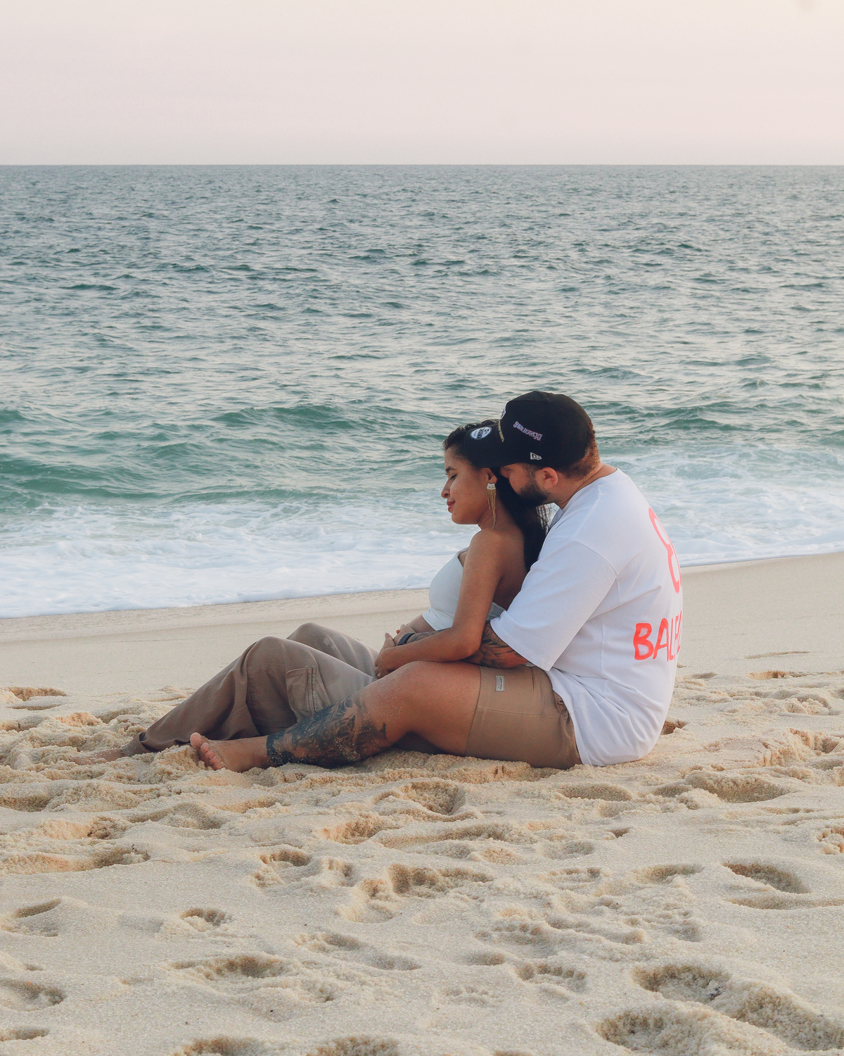Casal sentados na areia da praia de Itaipuaçu