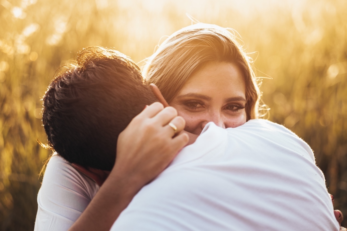 casal feliz segurando nuca do noivo olhar sobre ombro por do sol