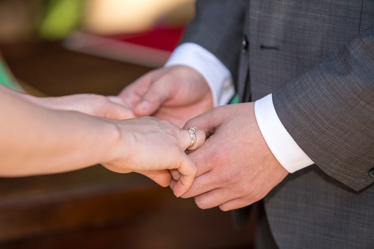 detalhes das mãos dos noivos fazendo votos.