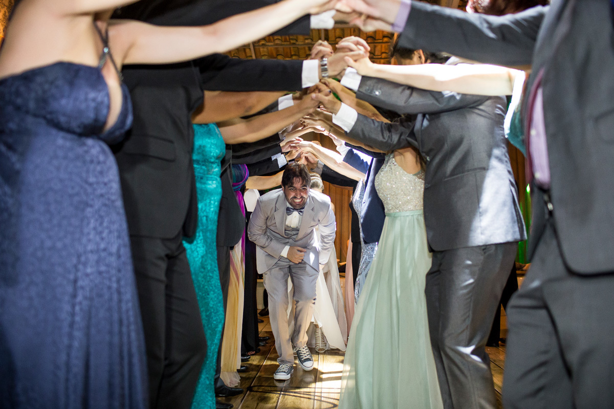 Noivos passando por baixo das mãos dos padrinhos