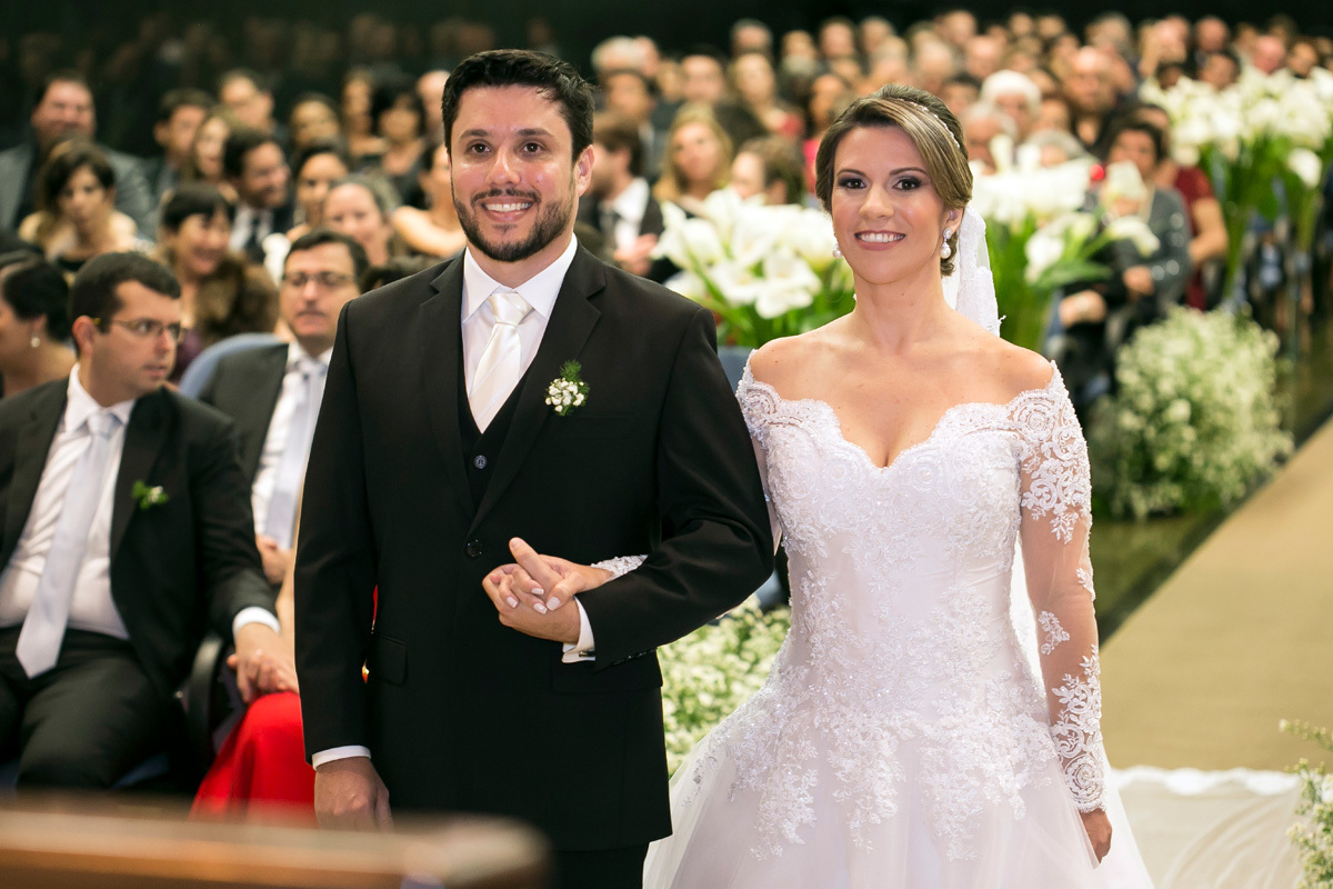 Noiva e noivo em sua cerimônia de casamento com os convidados atrás.