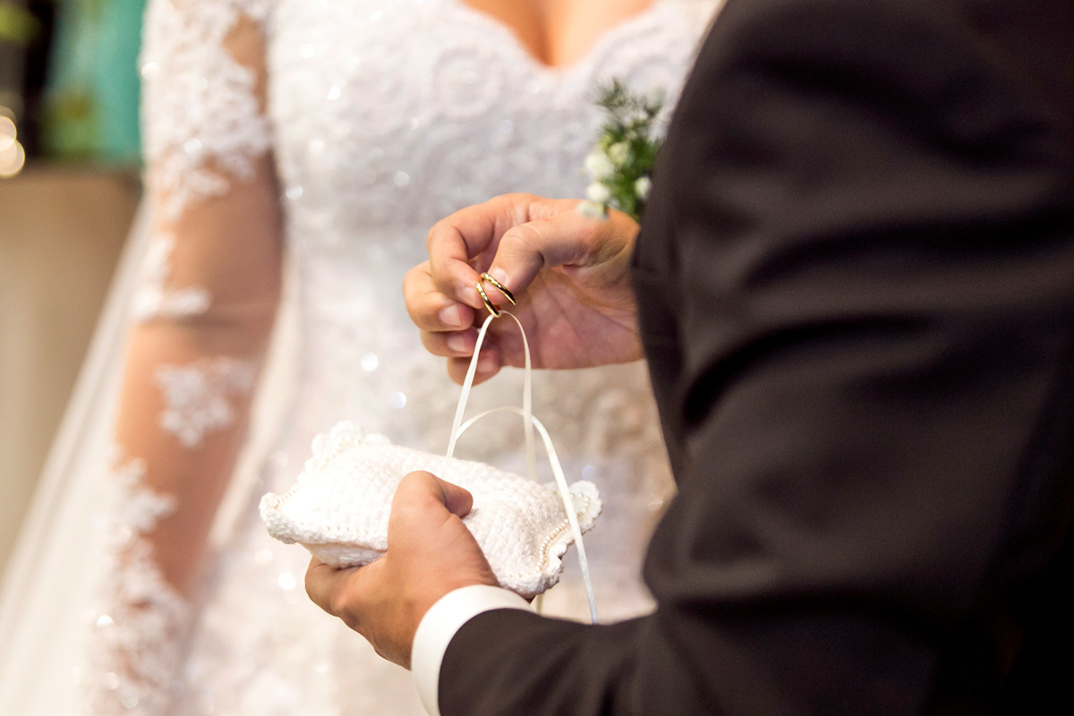 Noivo segurando as alianças de casamento.
