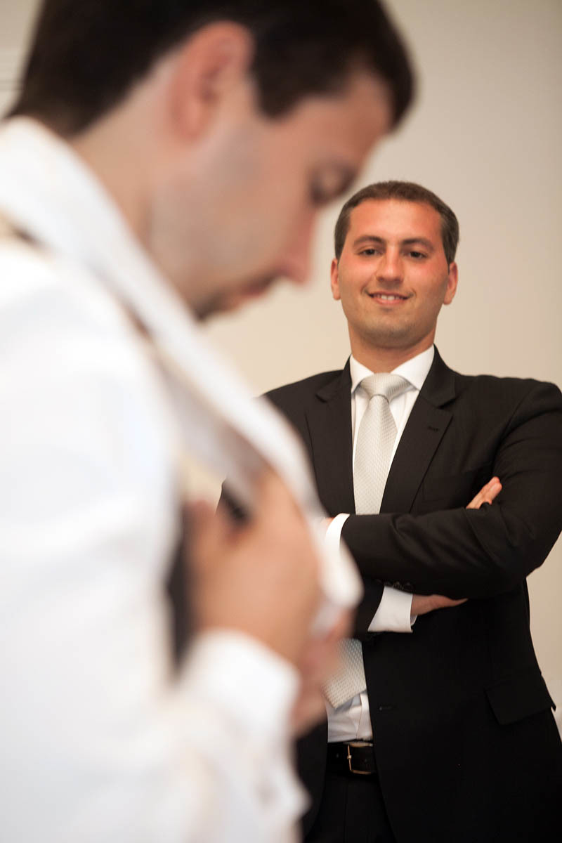 irmão do noivo observando o noivo colocar a gravata