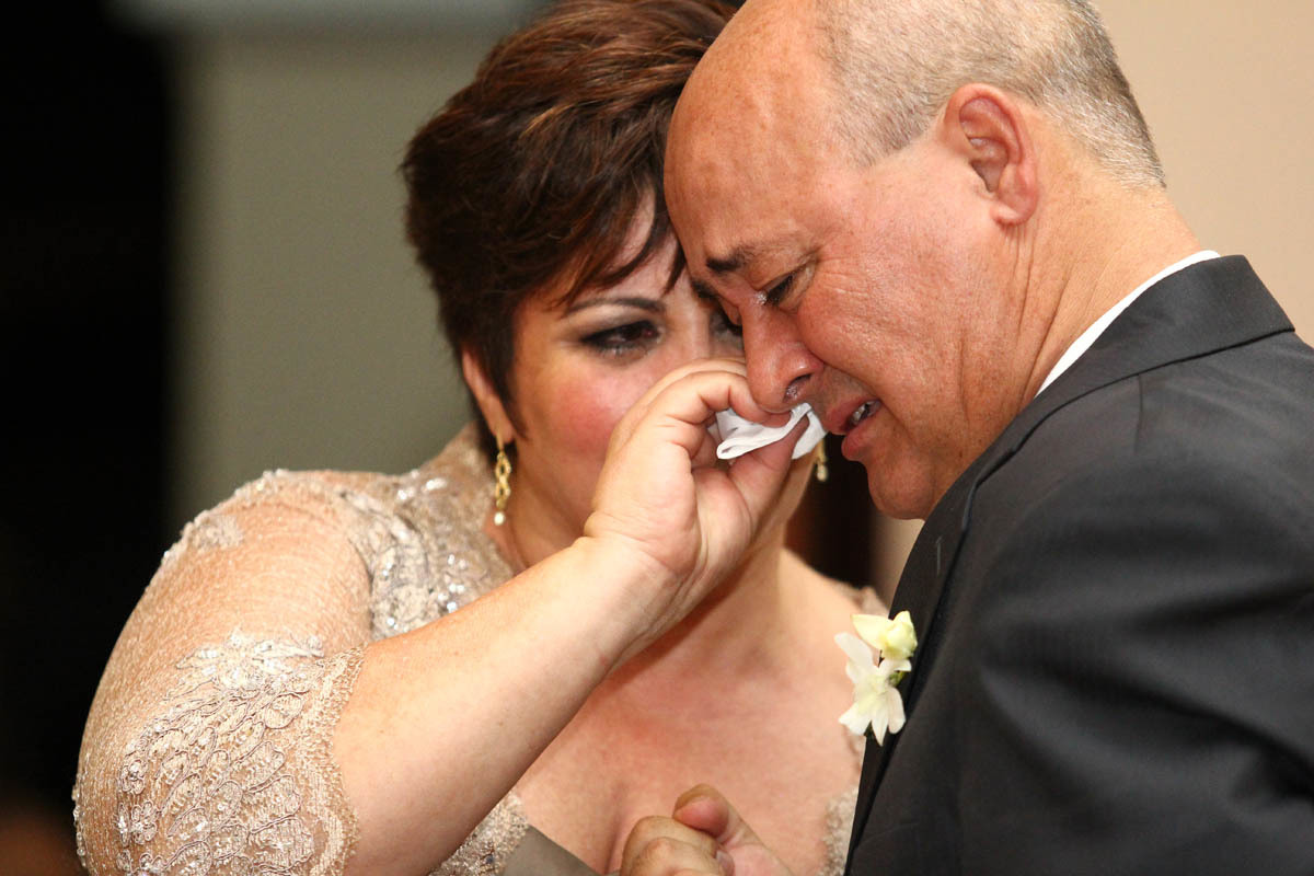 Mãe da noiva enxugando as lágrimas de seu esposo no casamento da Juliana e Fábio na Capela Estigmatinos em Ribeirão Preto 