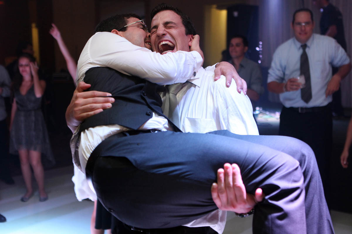 noivo sendo abraçado pelo seu melhor amigo em seu casamento.