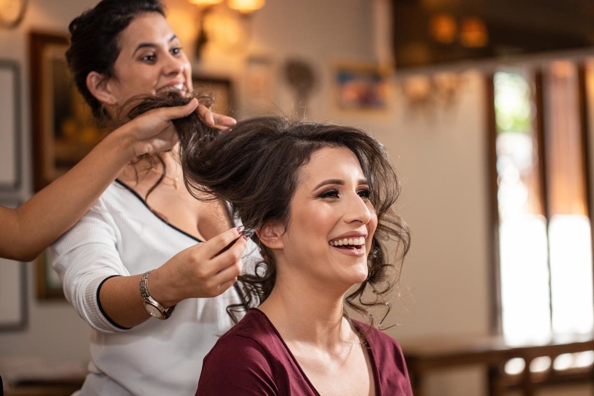 noiva sorrindo em seu making of enquanto arruma o cabelo