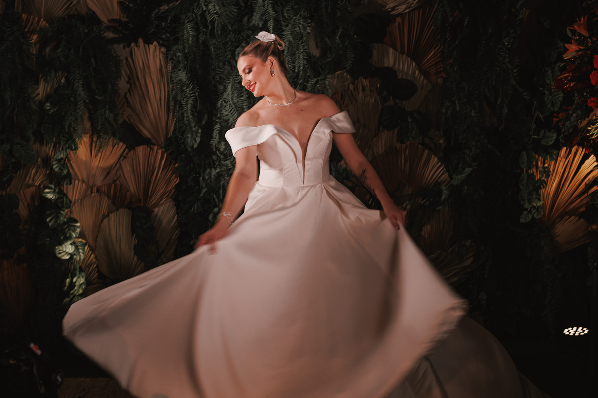 noiva de vestido branco sem renda de manga caída com decote v  e penteado preso foto em decoração boho verde com folhas inspiração para retratos da noiva