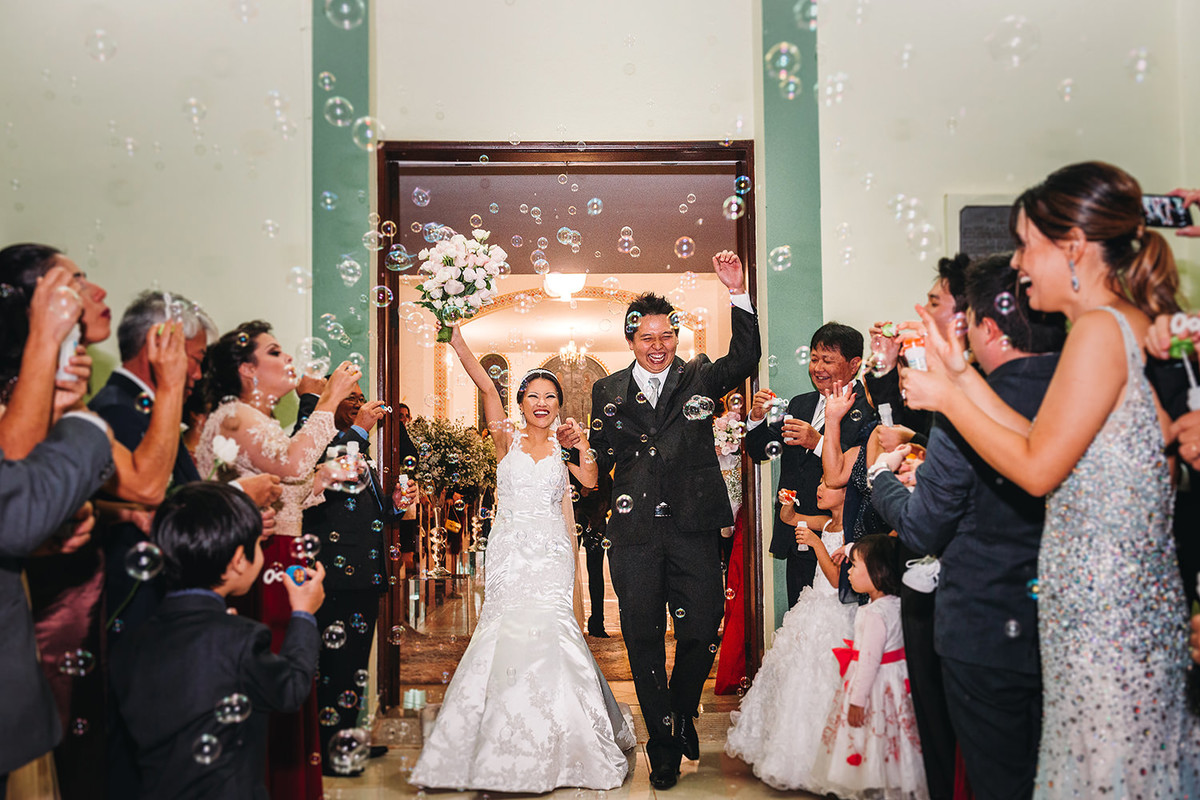 Foto dos noivos festejando o casamento na saida da igreja em Maringá-PR