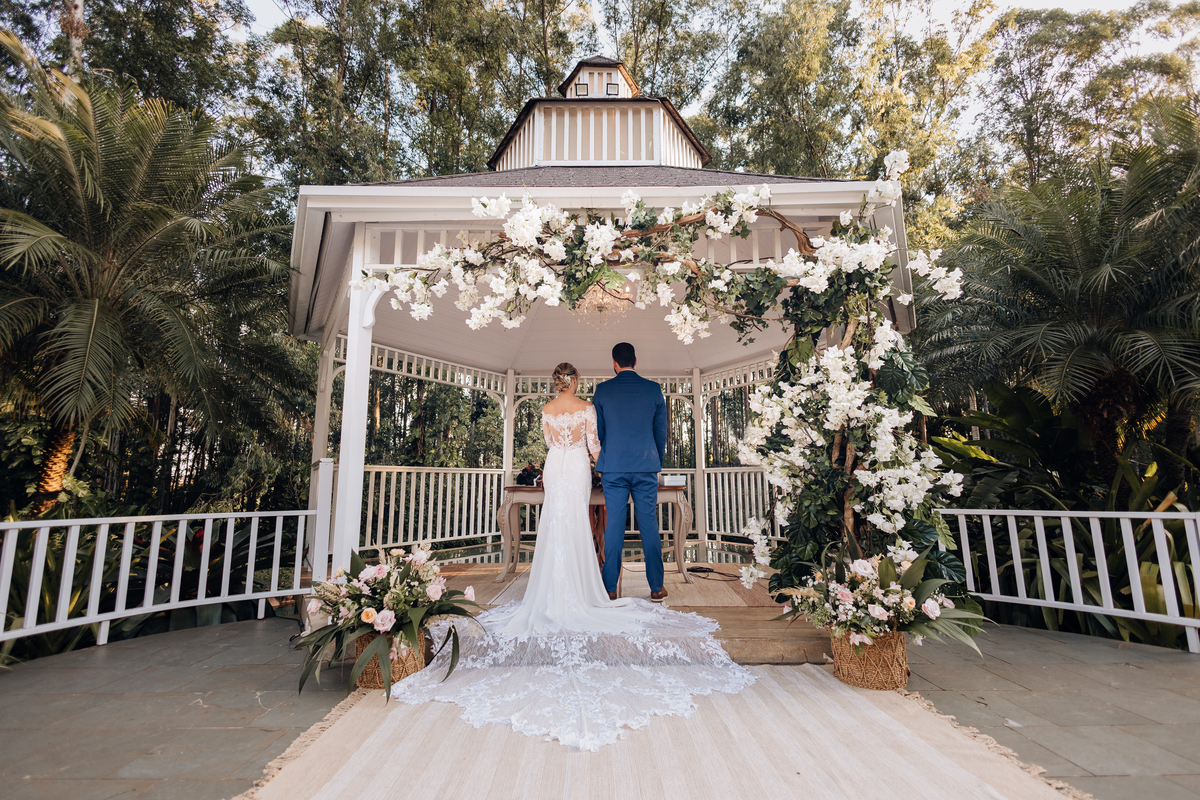 Decoração de arco de flores e folhagem com noivos no altar ao ar livre em Maringá  melhor fotografo de casamentos de maringá