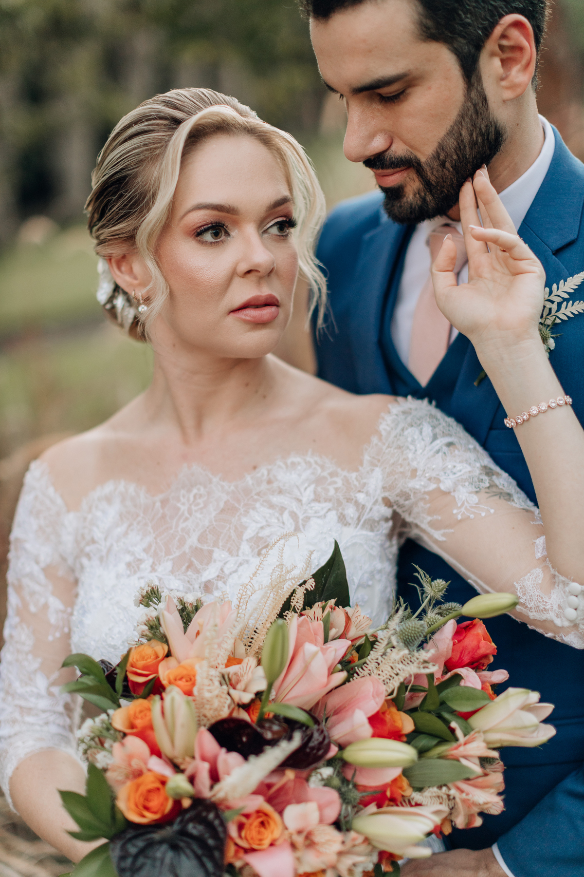 Noiva segurando seu buquê, com vestido de renda e penteado clássico 