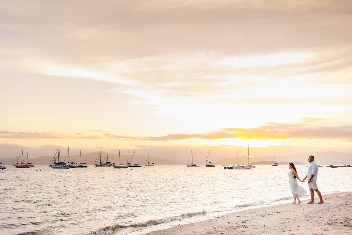 Fotografia de casal na praia durante o nascer do sol
