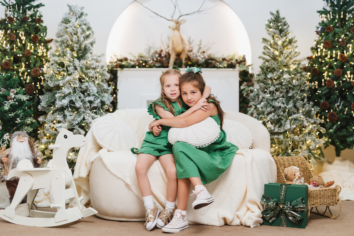 Fotografia de irmãos em cenário de Natal em Maringá.