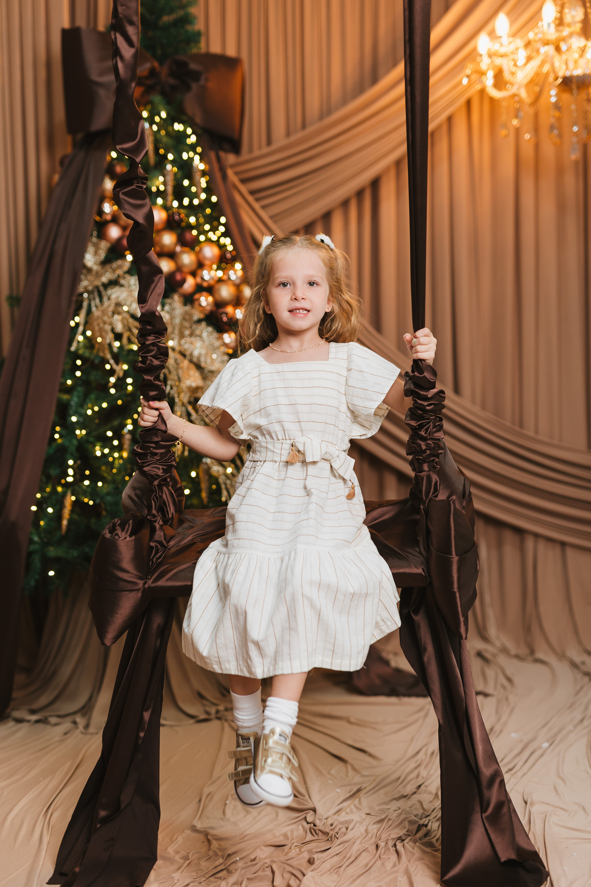 Foto infantil de Natal com cenário sofisticado e decoração natalina.