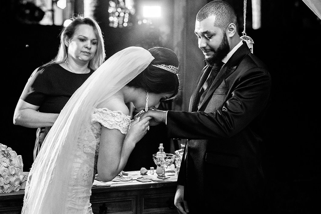 foto da noiva beijando a mão do noivo durante cerimonia religiosa 