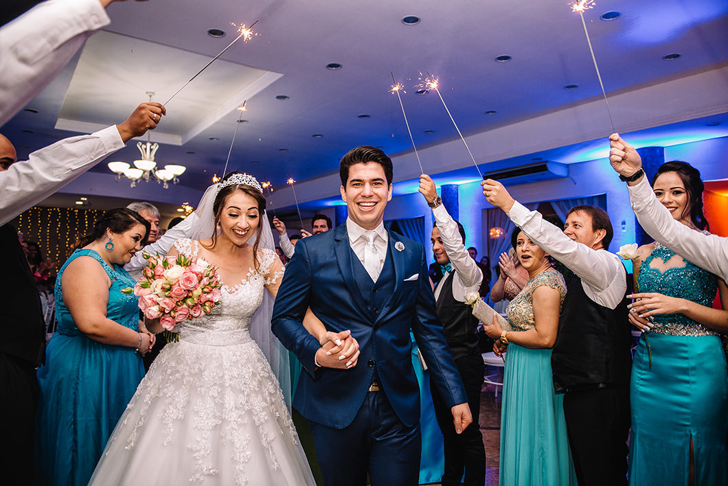 Saída dos noivos da cerimonia de casamento convidados com varetas de luz pisca pisca 