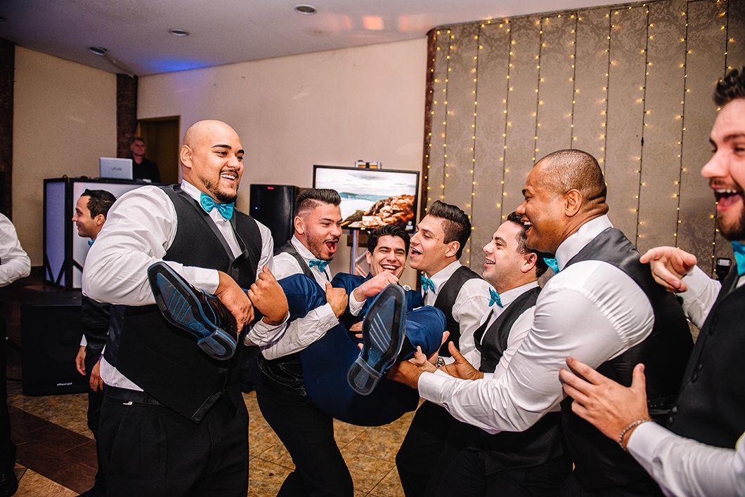 Amigos do noivo jogando o noivo para cima durante festa de casmamento