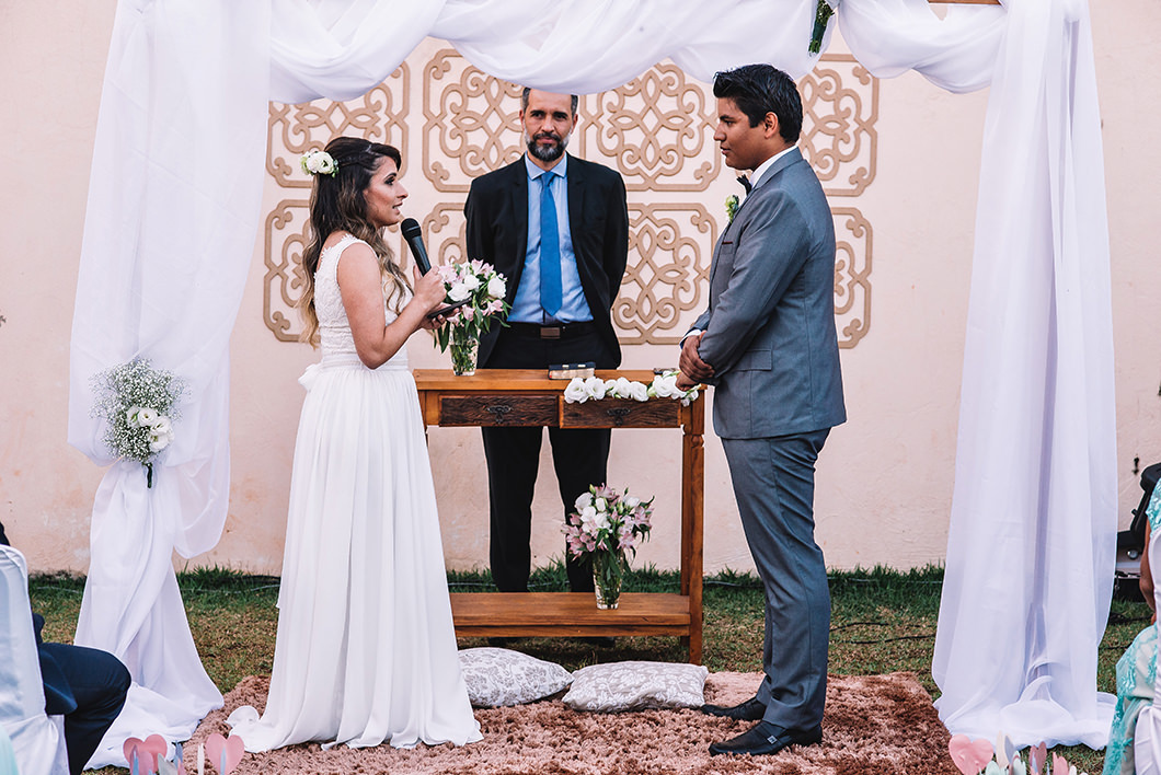 Noiva lendo votos para o noivo em cerimonia de casamento ao ar livre 