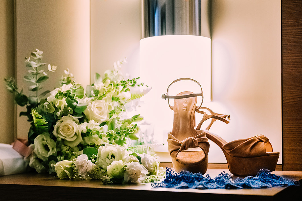 Detalhes do sapato da noiva com cinta liga azul e buque destruído da noiva 