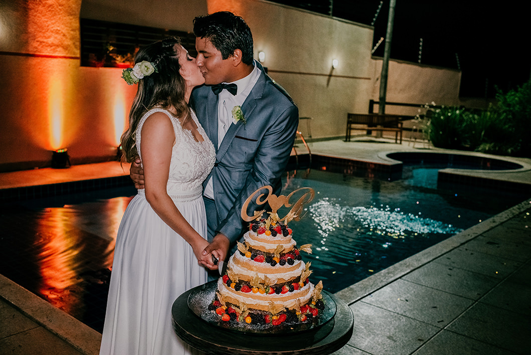 Fotografia de Casal se beijando na hora de cortar o bolo Naked  cake de casamento 