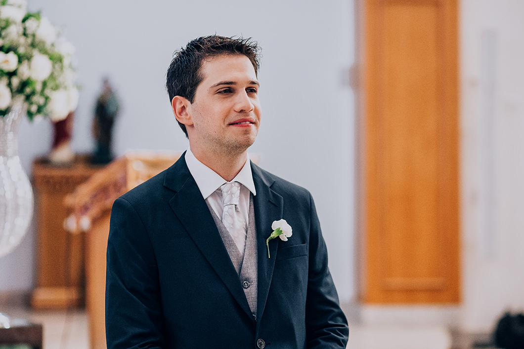 Foto do noivo olhando a entrada da noiva emocionado 