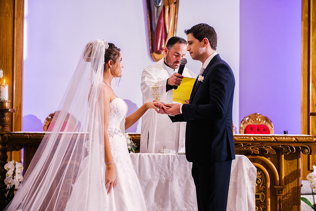 Noivos trocando aliança no altar de cerimonia religiosa 