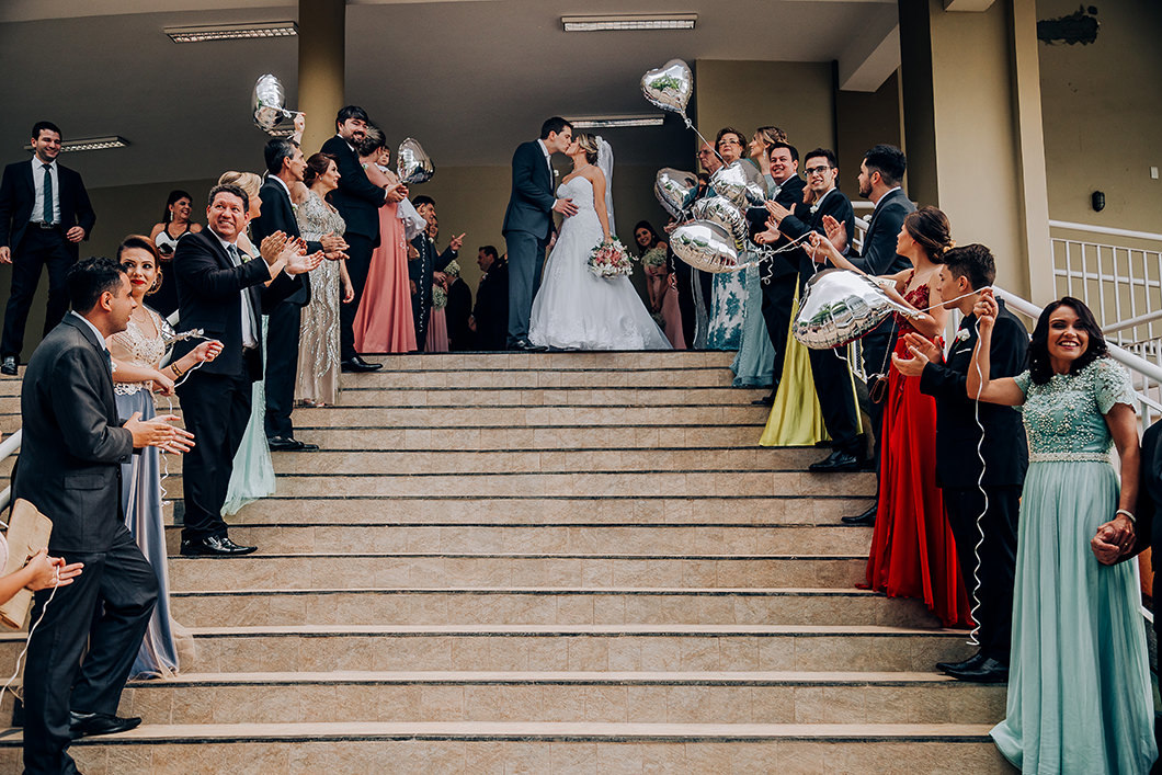 Foto dos noivos saindo da igreja catolica com balões metalizados 