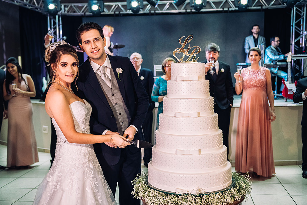 Foto tradicional  dos noivos cortando bolo  