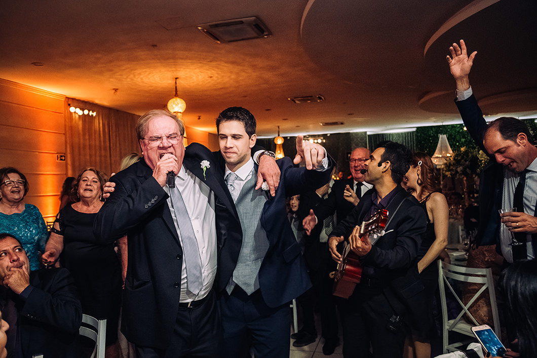 Pai do noivo cantando no jantar de casamento em fotografia de casamento espontânea 