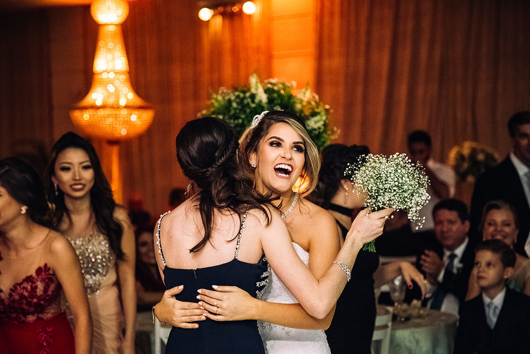 Noiva abraçando amiga que pegou o buque da noiva 