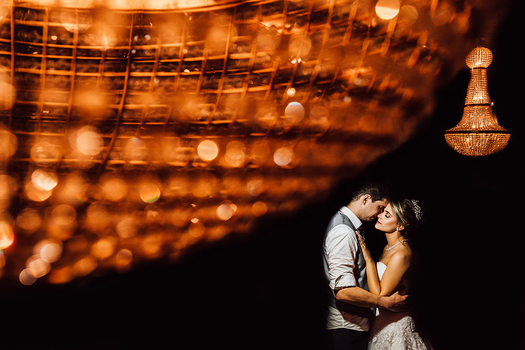 Rickardo Andrade fotografia dos noivos com lustre da decoração da festa 