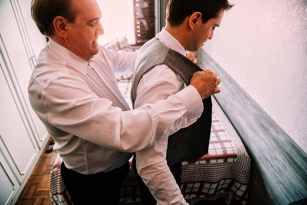 Foto do pai do noivo ajudando ele a se vestir 