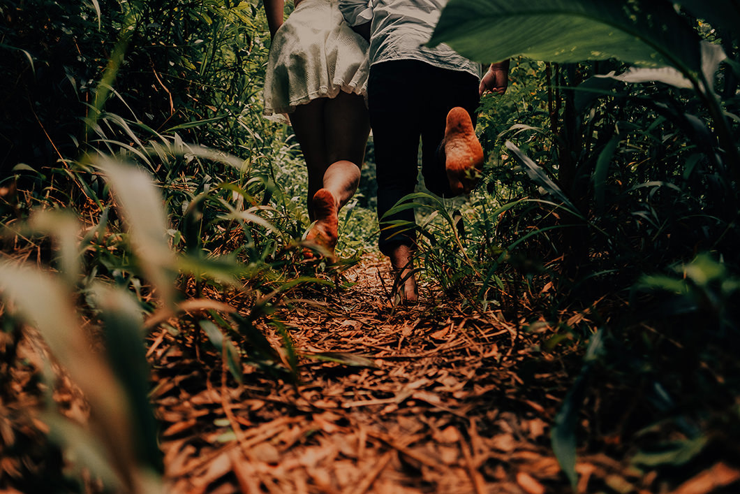 Foto divertida de casal correndo na natureza com pés descalços 