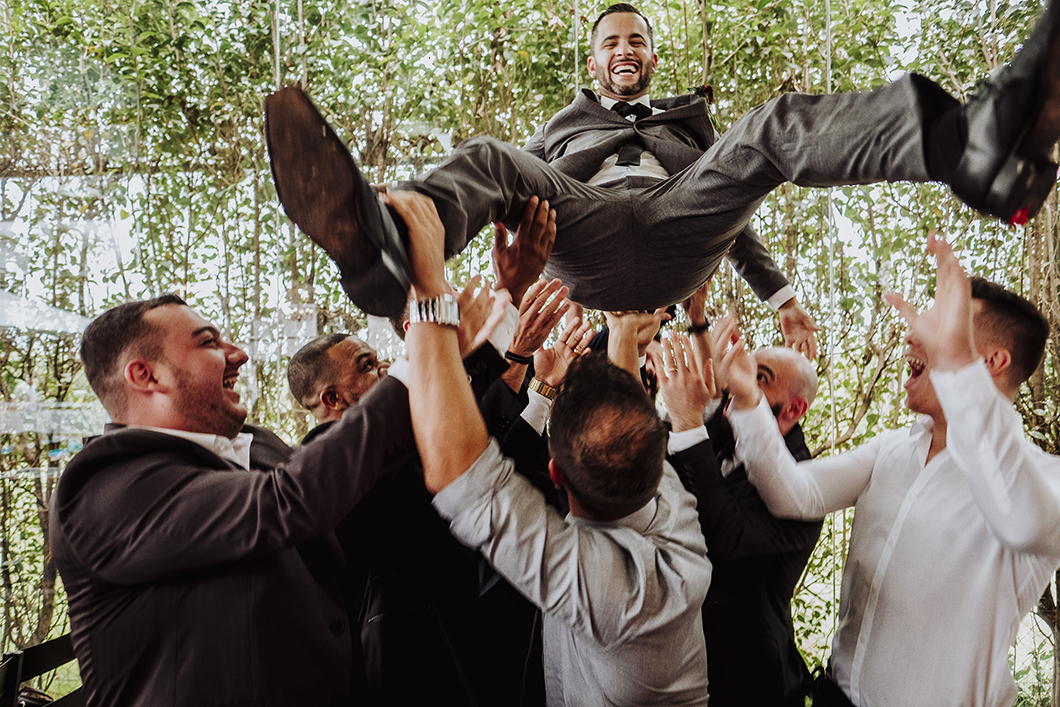 fotos de casamento de dia amigos do noivo jogando o noivo para cima 