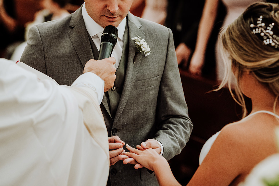 noivo colocando aliança na noiva em altar catolico 