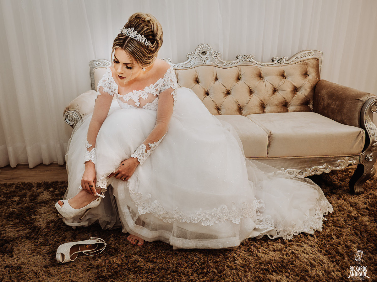 fotografia de casamento foto da noiva se vestindo com vestido classico e romantico de noiva 