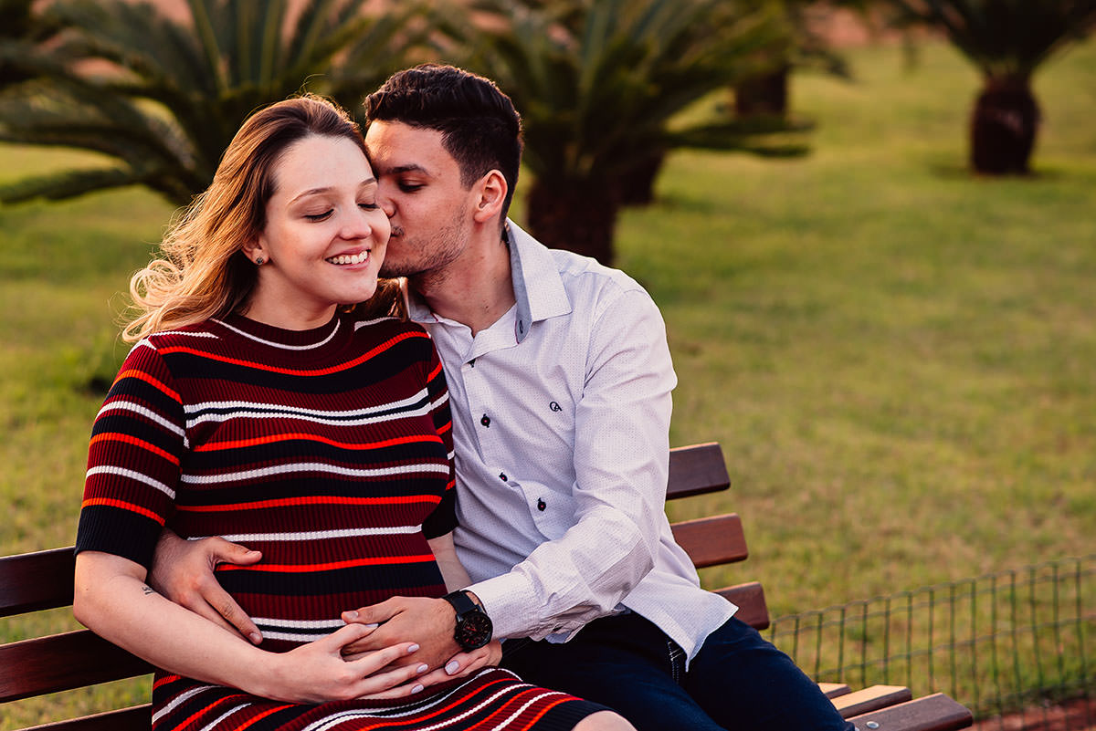 fotos de um casal sentados no banco da praca durante o ensaio fotografico de gestacao