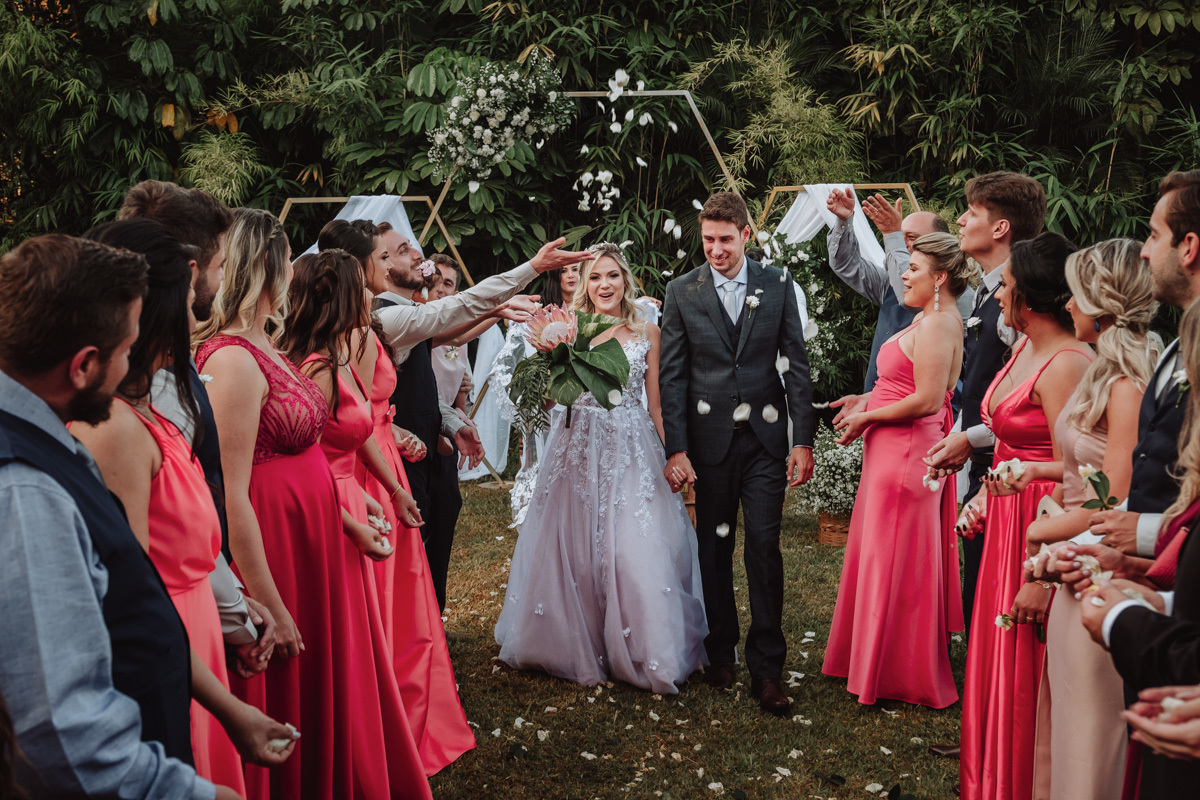 saida dos noivos em corredor de padrinhos com chuva de petá-las de rosas  