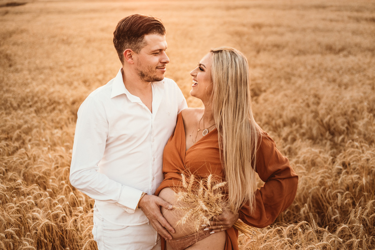 lindo ensaio de gestante com luz amarelada do sol em plantação de trigo 