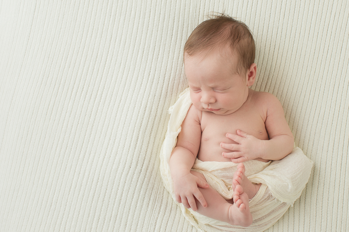 Foto feita na casa do cliente em Curitiba. Book Newborn do Benício com Gustavo Sousa. Pose de barriga para cima. Produção clean e tons de bege claro.