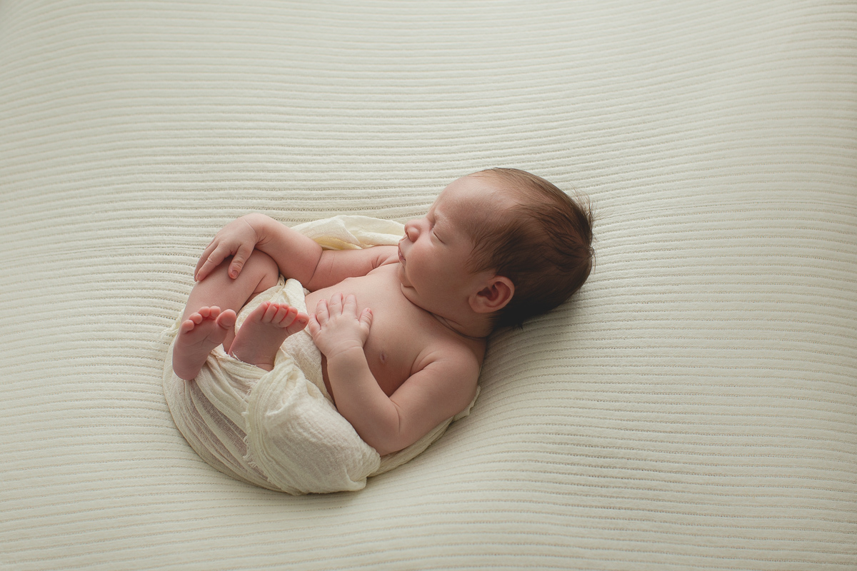 Foto feita na casa do cliente em Curitiba. Book Newborn do Benício com Gustavo Sousa. Pose de barriga para cima. Produção clean e tons de bege claro. Contra luz