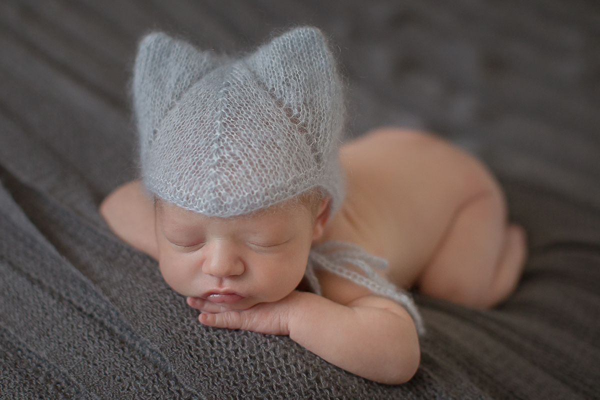  Foto feita no estúdio Gustavo Sousa Newborn em Curitiba. Book do Theo. Sessão de fotos. Touquinha. Deitado na pose do bracinho na manta cinza. Ângulo de frente