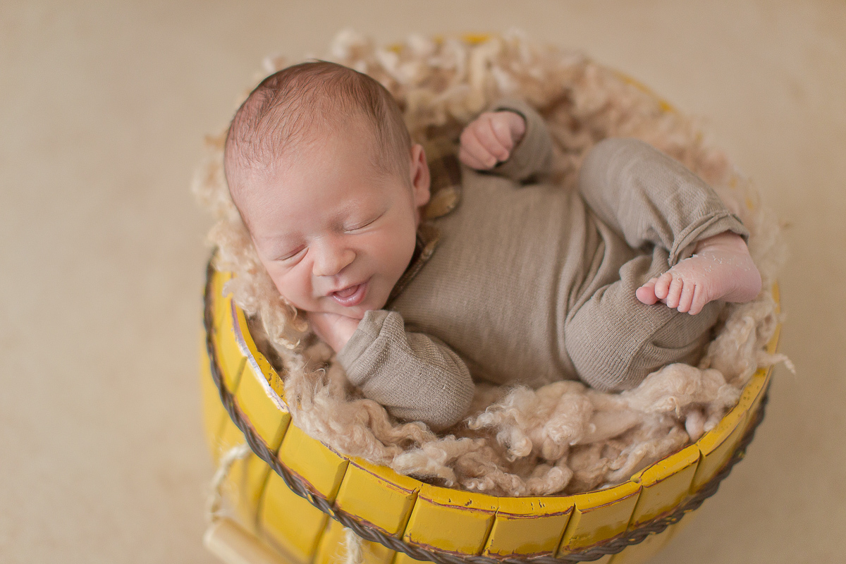  Foto feita no estúdio Gustavo Sousa Newborn em Curitiba. Book do Theo. Sessão de fotos. Pose de barriga para cima com balde amarelo e sorriso no rosto