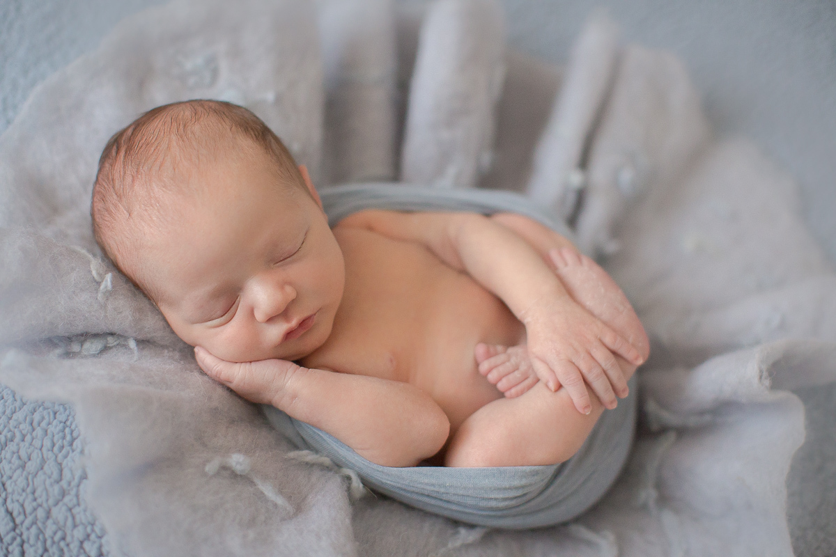  Foto feita no estúdio Gustavo Sousa Newborn em Curitiba. Book do Theo. Sessão de fotos. Pose de barriguinha para cima. Enrolado em paninho azul.