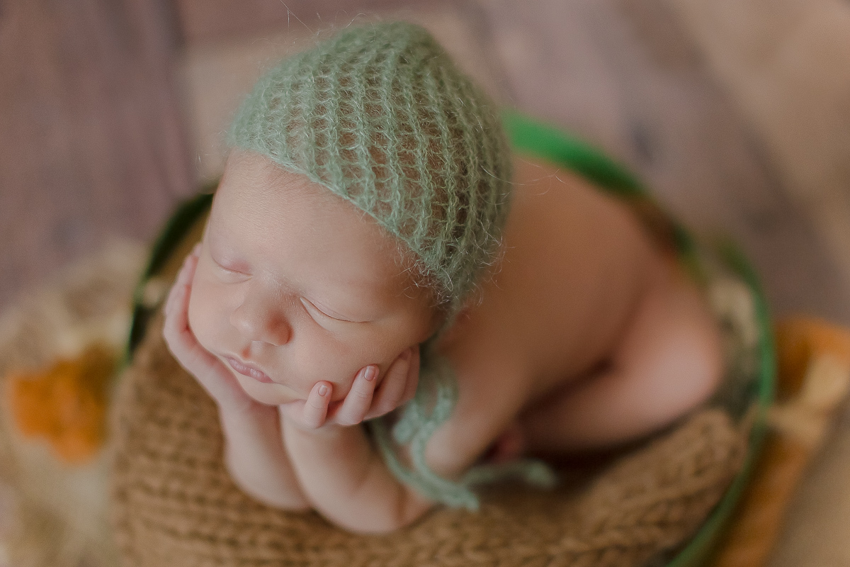  Foto feita no estúdio Gustavo Sousa Newborn em Curitiba. Book do Theo. Sessão de fotos. Pose do sapinho na contra luz com touca verde água. Dentro de baldinho verde. Fundo de madeira