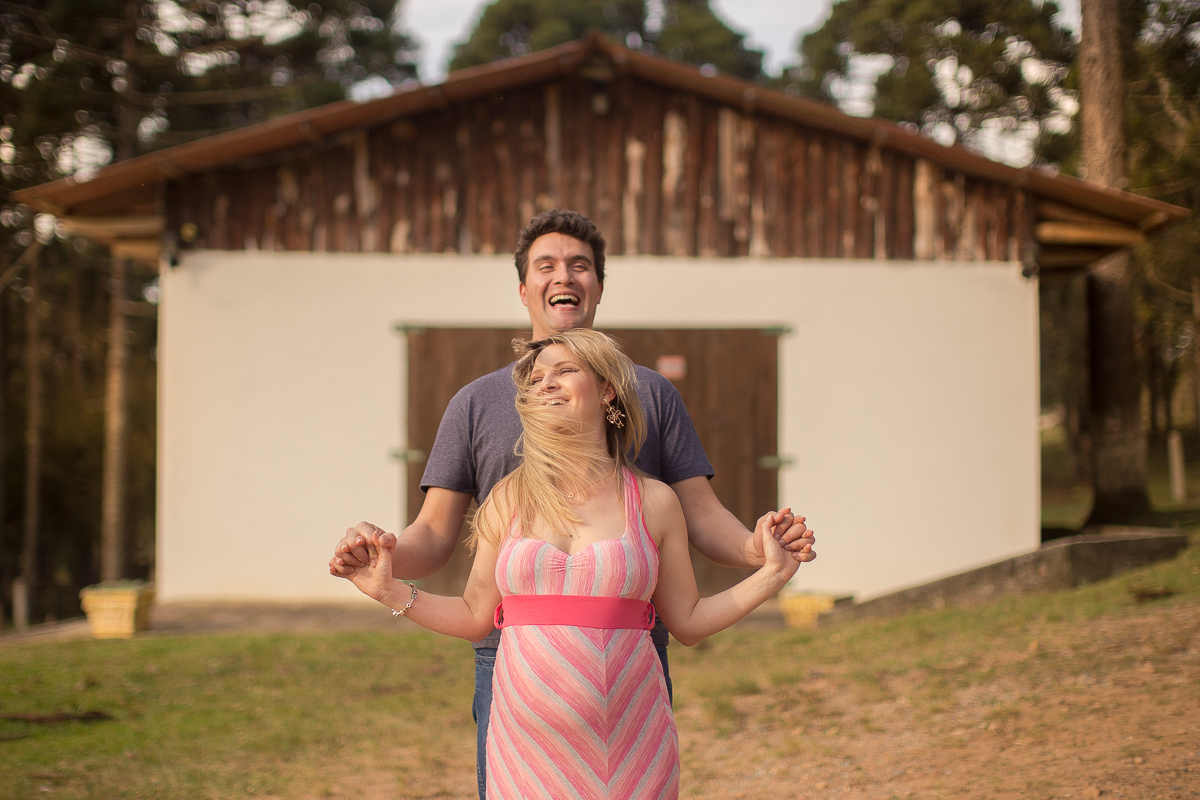Ensaio gestante da Pamela e Fabio com Gustavo Sousa fotografia em Curitiba. Book em externa em haras. Gravida com vestido listrado rosa e cinza.  com cachorro labrador preto. na frente da casa