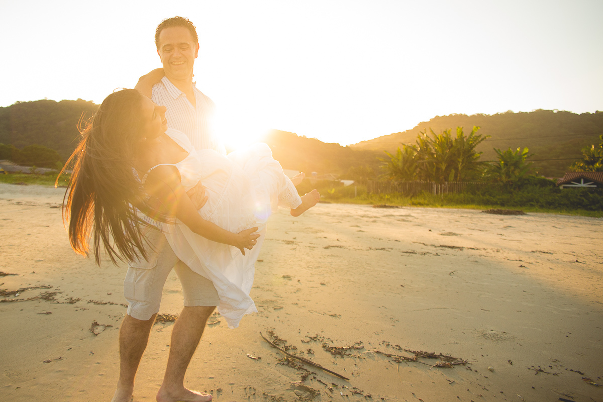 ensaio gestante em externa feito em curitiba com Gustavo Sousa Fotografia. Foto na praia com gestante no colo. por do sol.