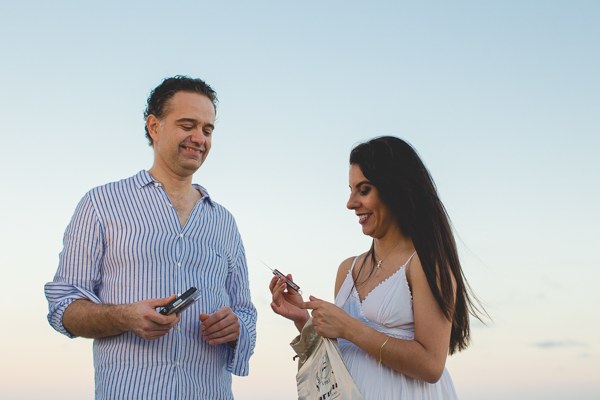 ensaio gestante em externa feito em curitiba com Gustavo Sousa Fotografia. Foto na praia com gestante no colo. por do sol. Trazendo objetos.