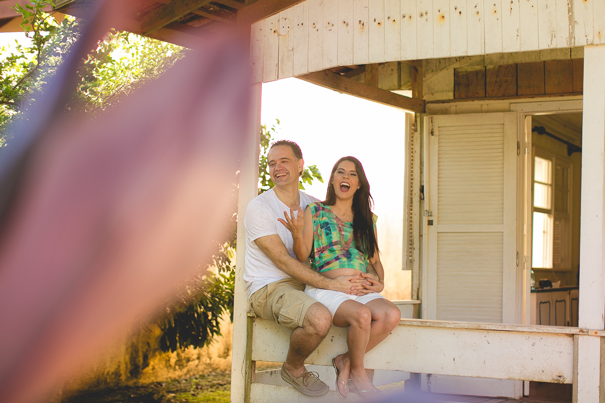 ensaio gestante em externa feito em curitiba com Gustavo Sousa Fotografia. fotografia expontânea na frente da casa antiaga.